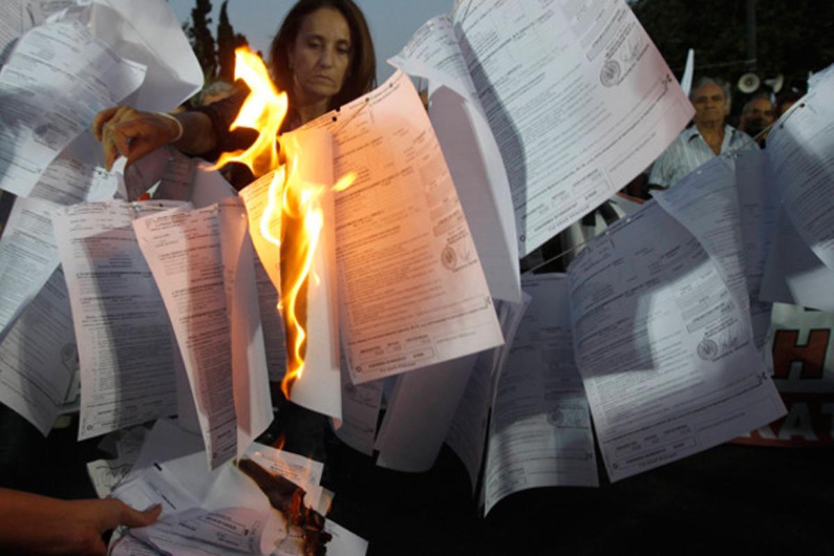 Membres del sindicat comunista PAME es congreguen a Atenes i cremen papers que anuncien un nou impost sobre la renda per part del govern grec.