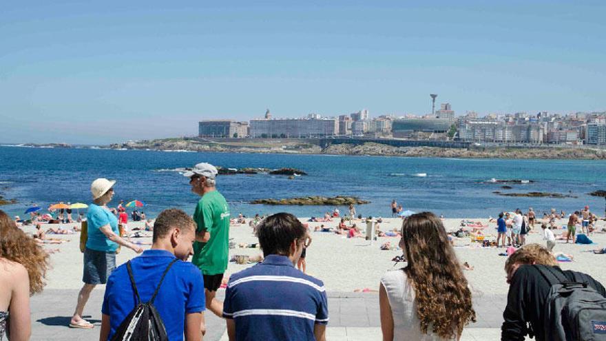 Veraneantes disfrutando del buen tiempo en la playa de Riazor.