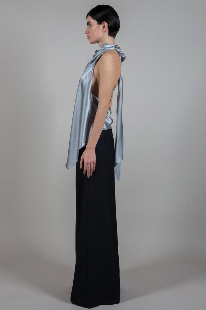 Detalle de la blusa metalizada de seda con escote a la espalda de Attire que Laura Escanes ha lucido en un look informal con jeans y botas