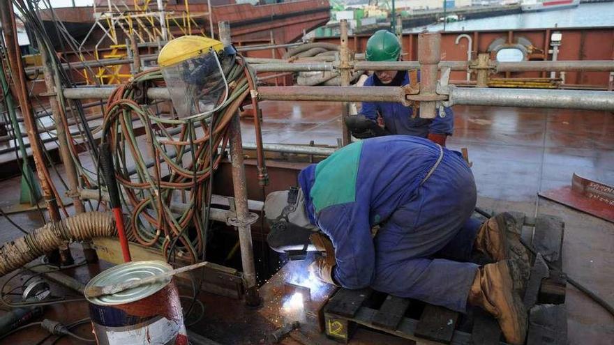 Dos empleados de un astillero gallego trabajan en la construcción de un barco.