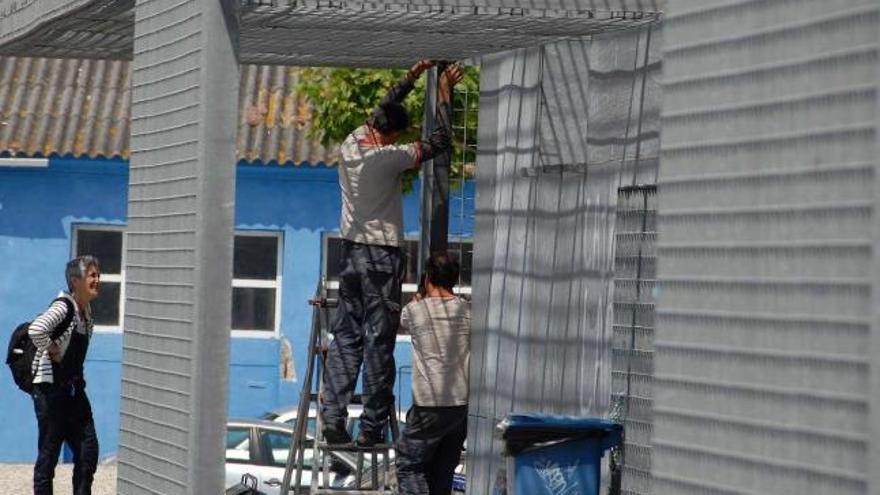 Trabajadores instalan los paneles que en teoría iban a reducir el ruido de las casetas de los marineros.// Gonzalo Núñez