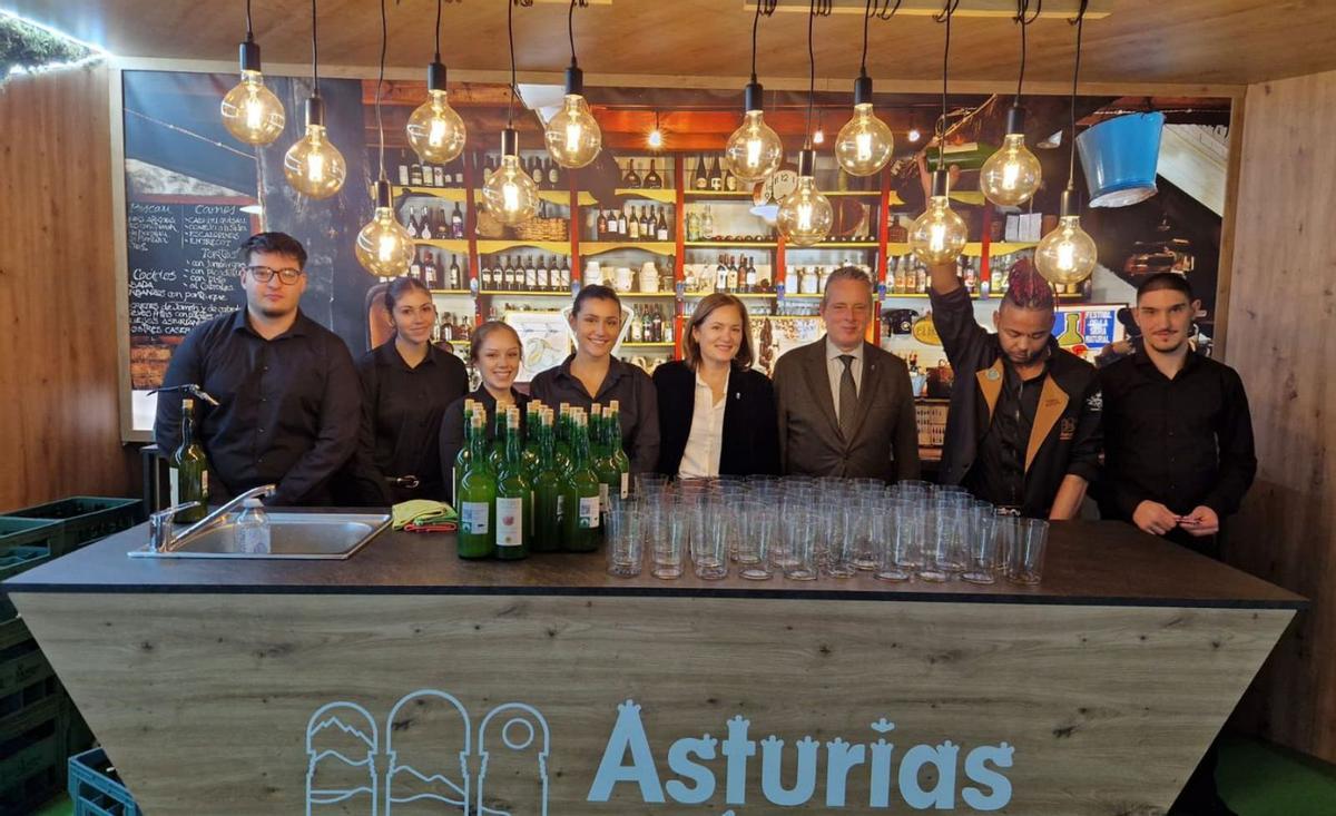 Marcelino Marcos, junto a la directora de Agroalimentación, Begoña López –tercero y cuarta por la derecha–, y los escanciadores y camareros del chigre del stand de Asturias. | PRINCIPADO