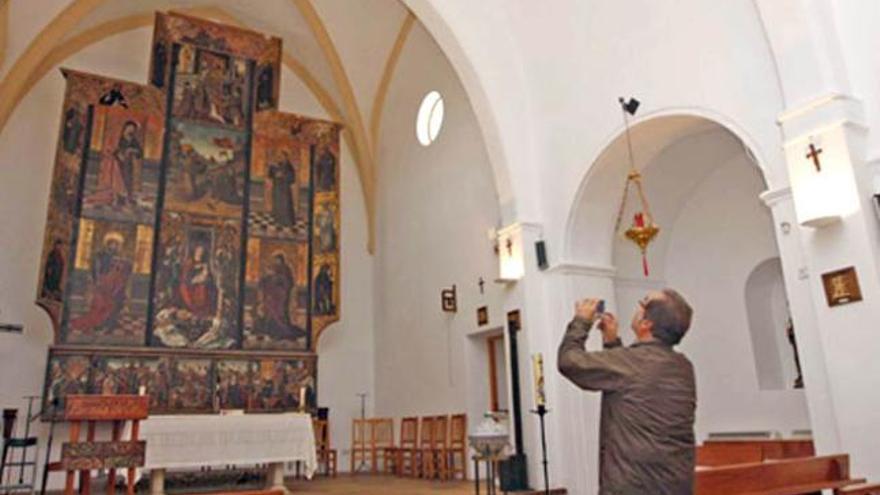 Una persona toma una fotografía al retablo de la iglesia de Jesús.