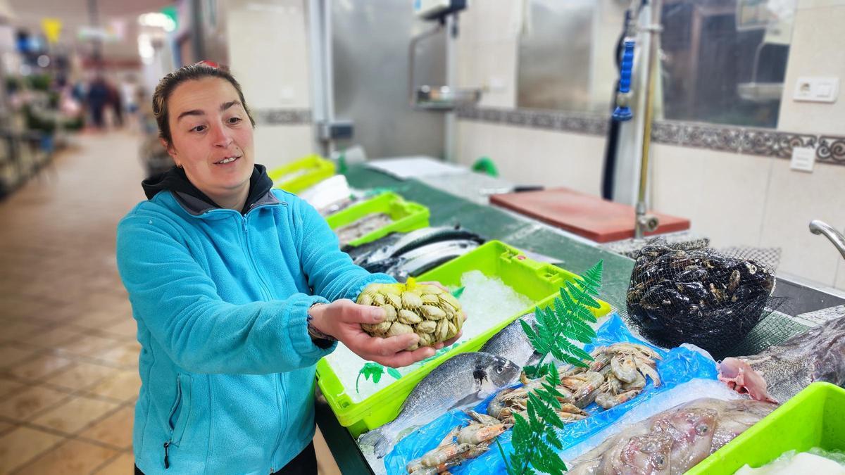 María Sixto, con una bolsa de almejas en su pescadería. | A. Velasco