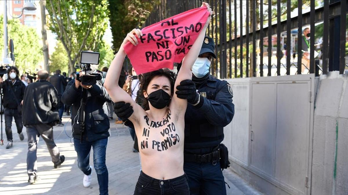 A Femen activist with her bare chest reading  No vote neither permission to fascism  raises a signs reading  Not another step to fascism  during a protest against Spain s far-right Vox party outside a polling station in Madrid during the Madrid regional elections on May 4  2021  - Madrid is voting in an early regional election the incumbent conservative Popular Party is expected to win comfortably  dealing a blow to Spain s Socialist prime minister  (Photo by PIERRE-PHILIPPE MARCOU   AFP)