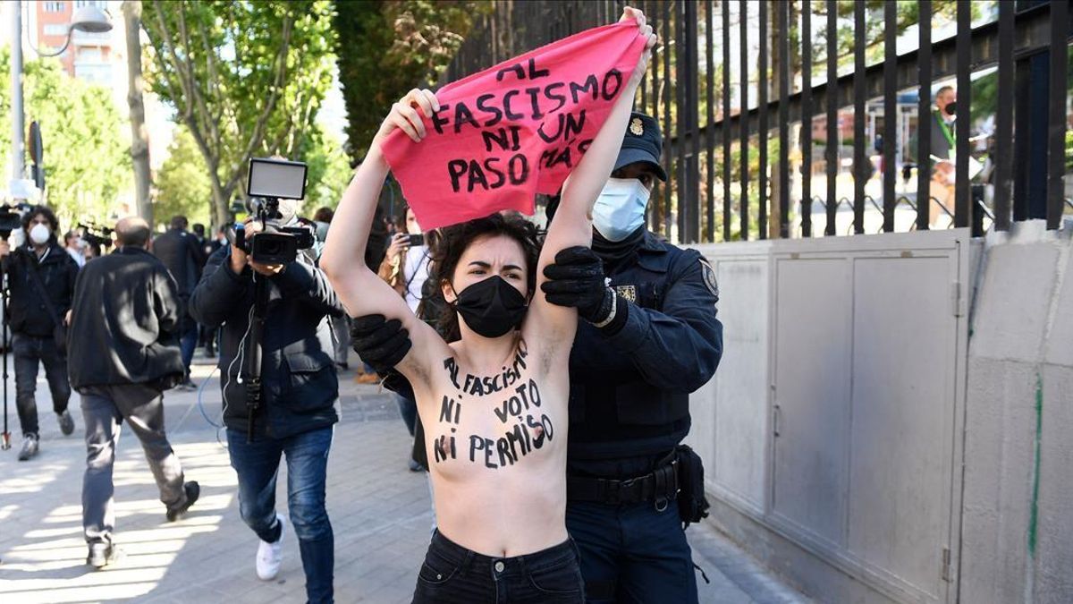 A Femen activist with her bare chest reading No vote neither permission to fascism raises a signs reading Not another step to fascism during a protest against Spain s far-right Vox party outside a polling station in Madrid during the Madrid regional elections on May 4 2021 - Madrid is voting in an early regional election the incumbent conservative Popular Party is expected to win comfortably dealing a blow to Spain s Socialist prime minister (Photo by PIERRE-PHILIPPE MARCOU AFP)