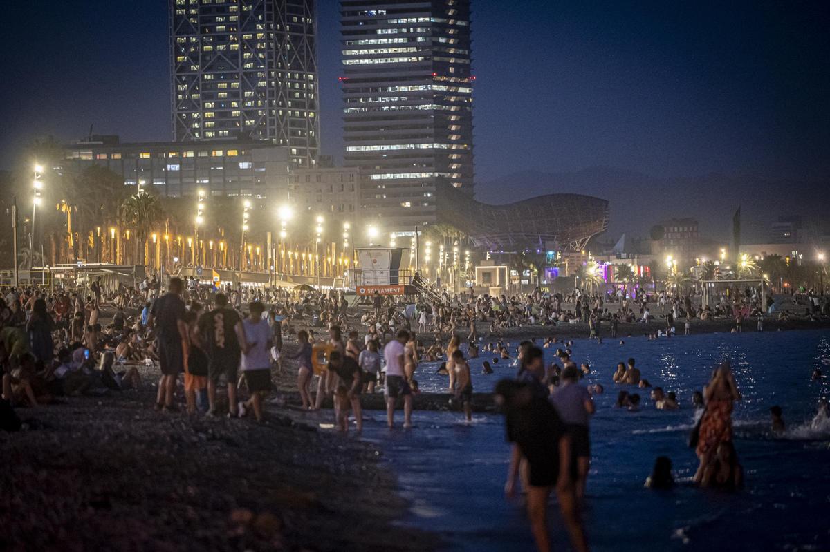 Noche tórrida en la playa. Los barceloneses combaten el intenso calor de agosto con baños nocturnos en las playas. En la imagen, la Barceloneta, repleta de gente, la noche del 23 de agosto