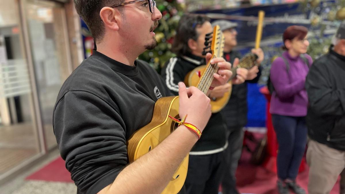 Cuadrillas de jóvenes murcianos interpretan villancicos en una plaza de abastos de Murcia.