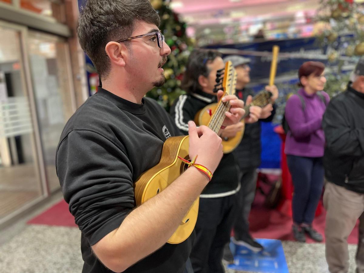 Cuadrillas de jóvenes murcianos interpretan villancicos en una plaza de abastos de Murcia.