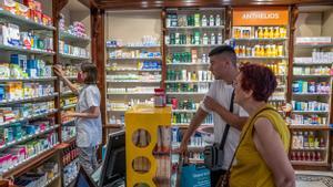 Dos clientes de una farmacia, sin mascarilla, este martes, antes de que entre en vigor oficialmente la retirada de los tapabocas.