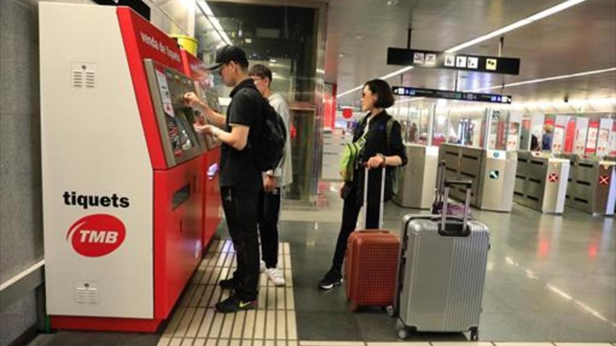 Unos turistas compran billetes en una máquina expendedora del metro.