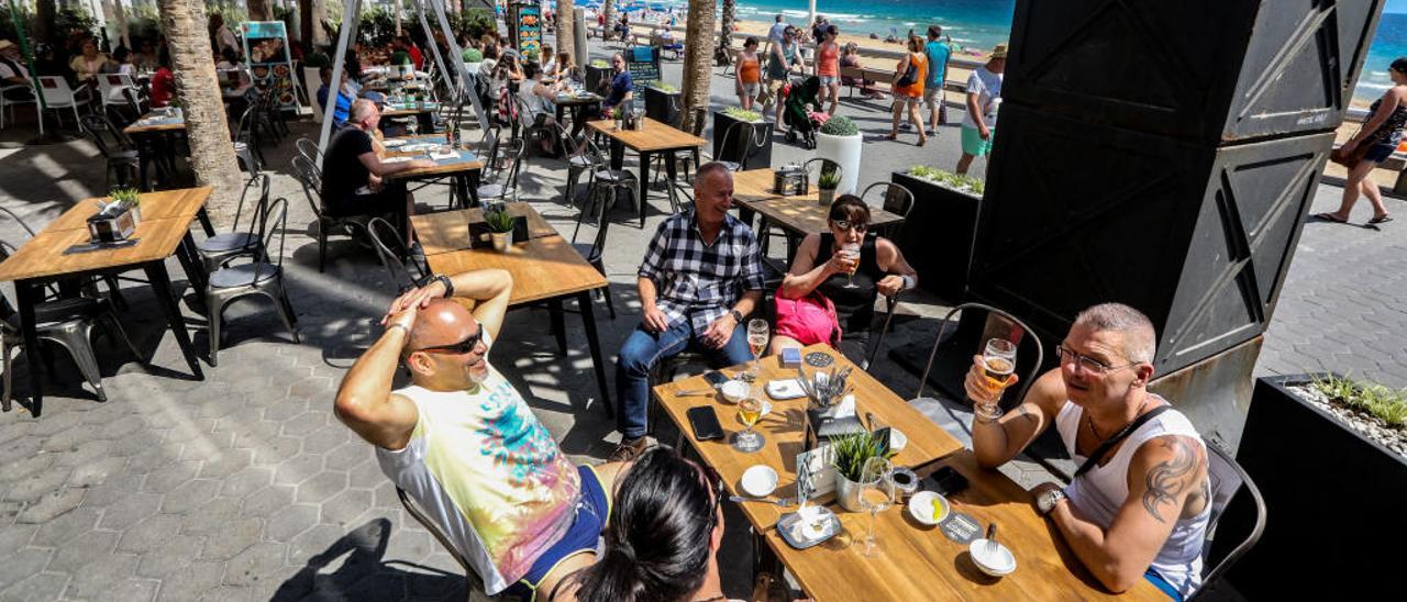 Unos turistas consumen en una terraza de Benidorm con numerosas mesas vacías.