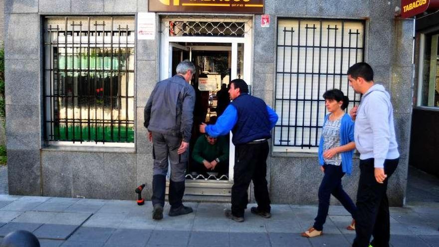 Dos operarios reparan la verja de acceso al estanco de Pontecesures.  // Iñaki Abella