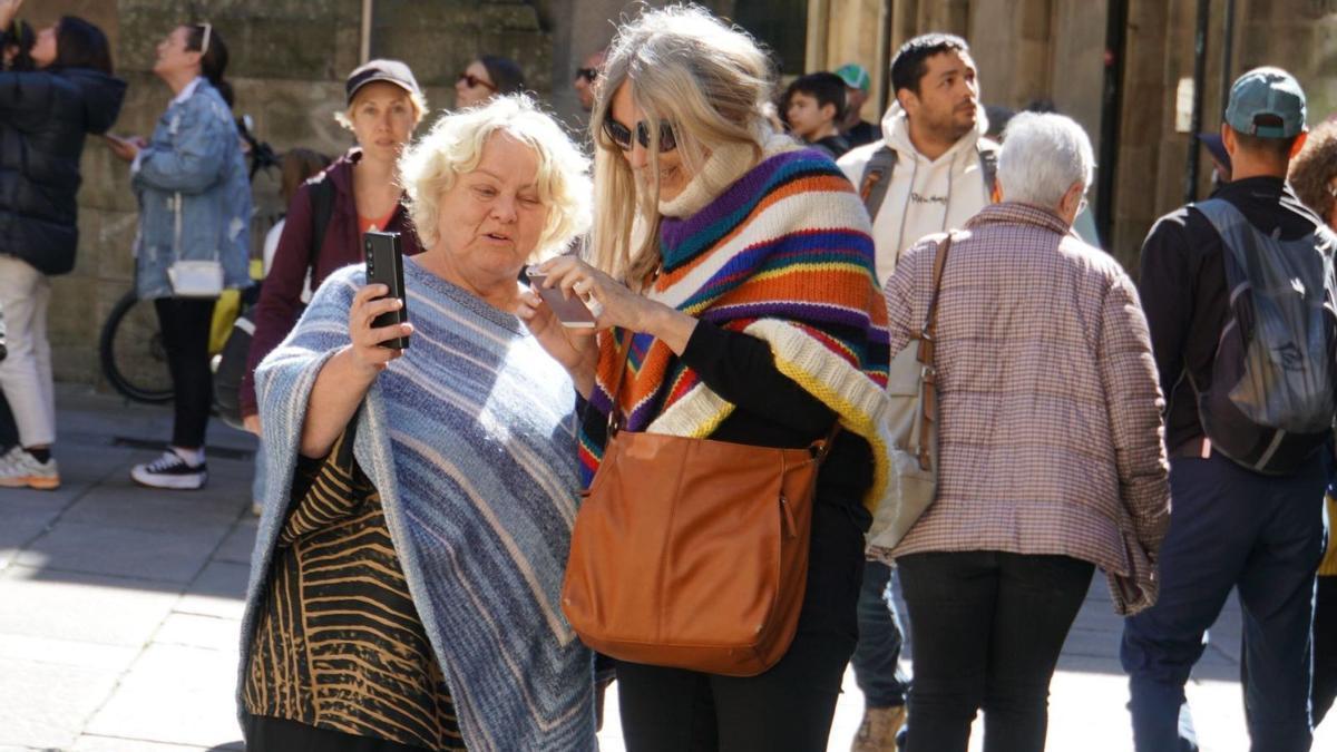 Dos turistas consultan sus móviles durante una visita al casco histórico coincidiendo con la celebración del pasado Jueves Santo.