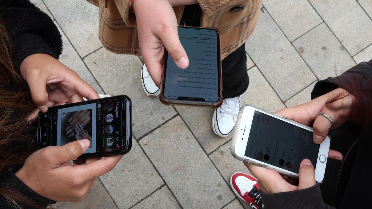 Jóvenes usan sus teléfonos móviles.
