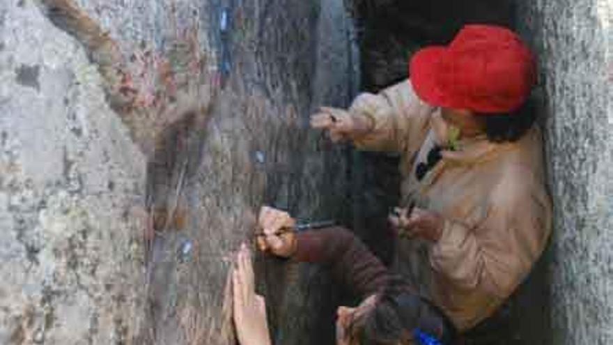 Socorro López trabajando en la reproducción de los grabados en la pared del abrigo.