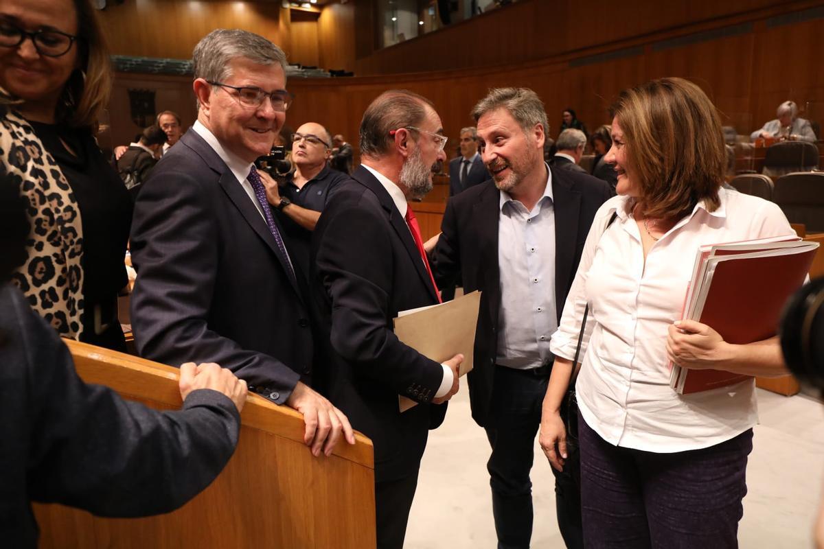El presidente de Aragón, Javier Lambán, saluda a José Luis Soro, consejero de Vertebración del Territorio, en un momento de la segunda jornada del debate del estado de la comunidad
