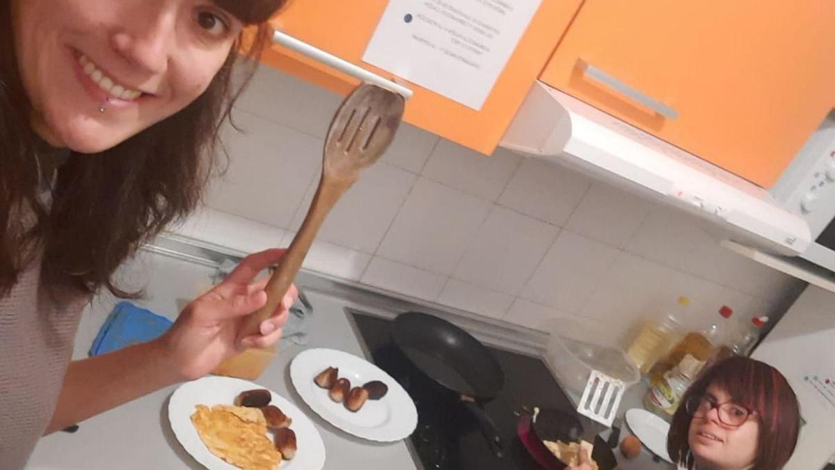 Una de las jóvenes emancipadas de 
la Fundación Down Zaragoza haciendo 
la cena con el apoyo de la «mediadora»”. | SERVICIO ESPECIAL