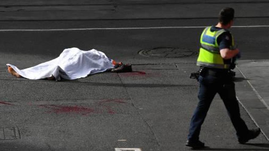 Un policia treballa a prop del cos de la víctima mortal al lloc dels fets