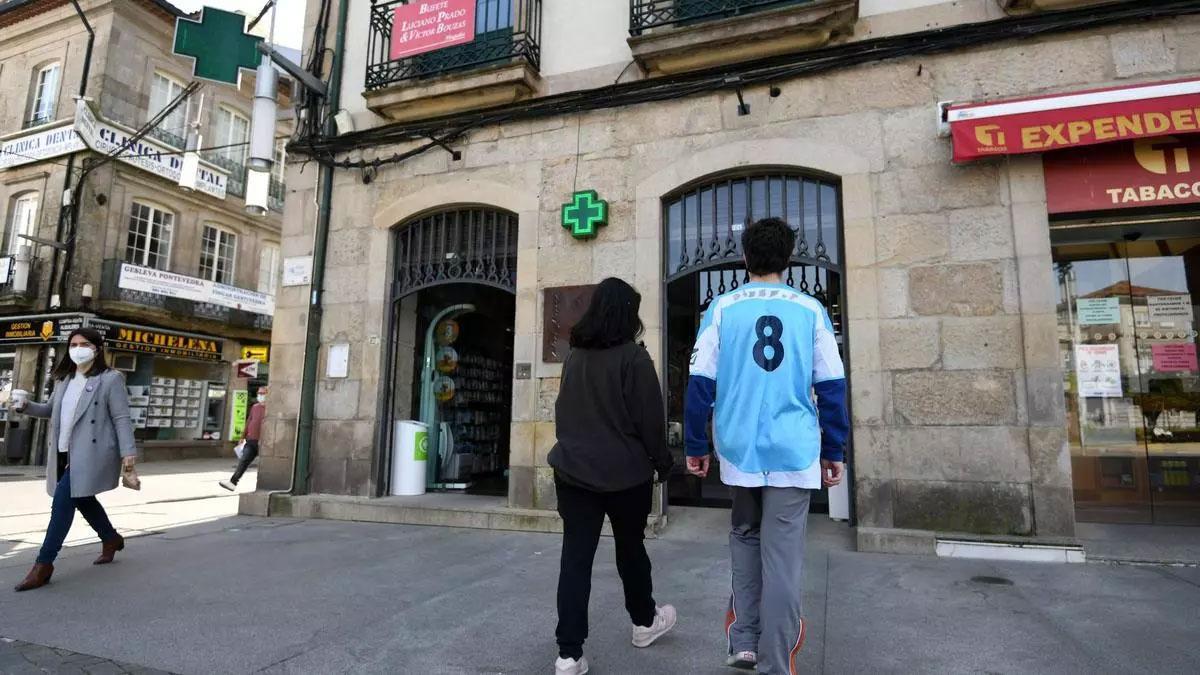 Unos adolescentes delante de una farmacia.