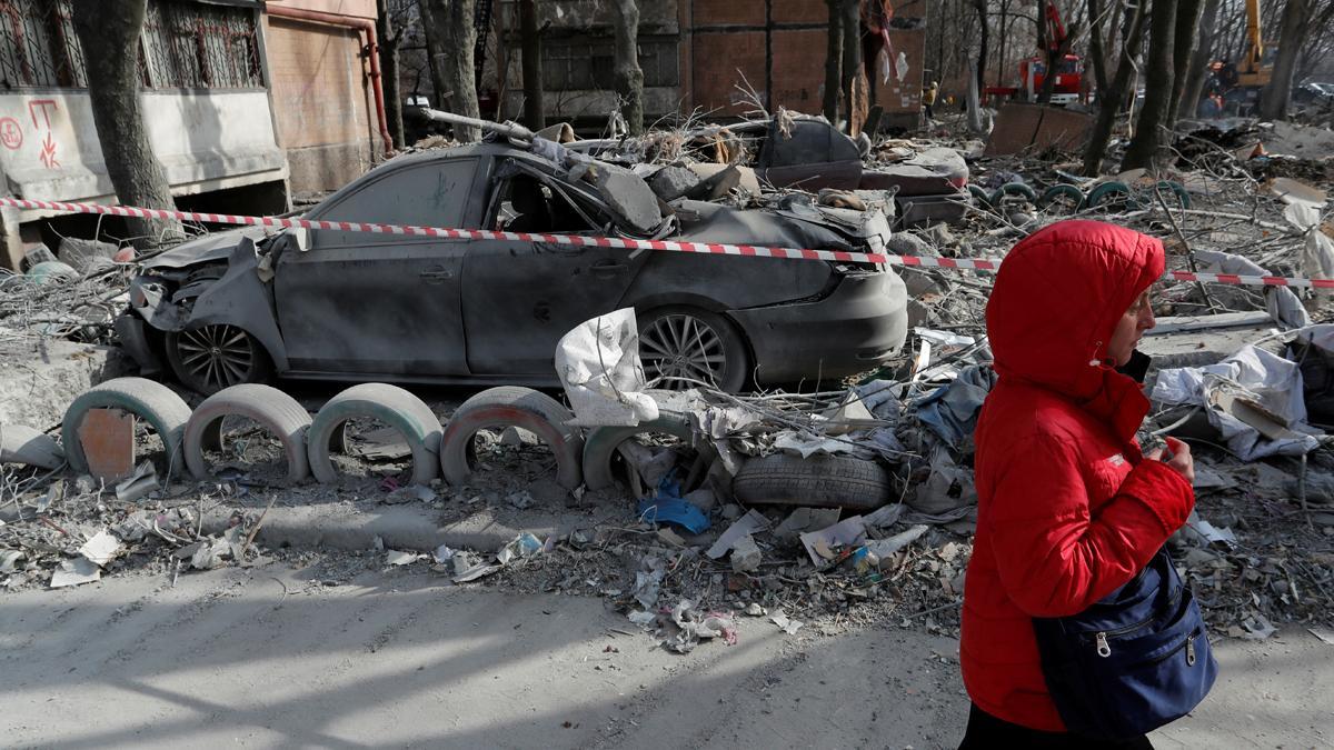 Una mujer pasa junto a autos destrozados junto a un edificio residencial dañado por los bombardeos durante el conflicto entre Ucrania y Rusia en la ciudad de Donetsk