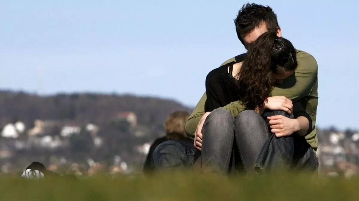 Una pareja se abraza en un parque.