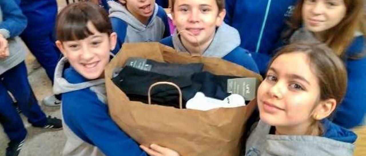 Un grupo de niños sostiene una bolsa con ropa para los usuarios de la Cocina.