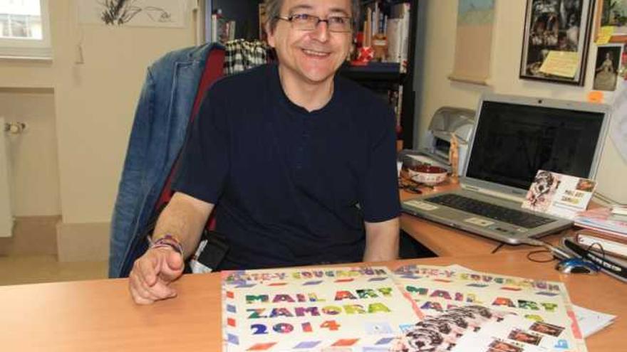 El artista y profesor Miguel Elías Sánchez con materiales de la muestra y su postal en su despacho del Campus.