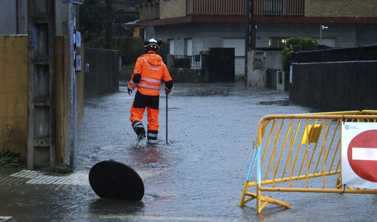 Un efectivo de Protección Civil, en medio de la Rúa do Santo, inundada.