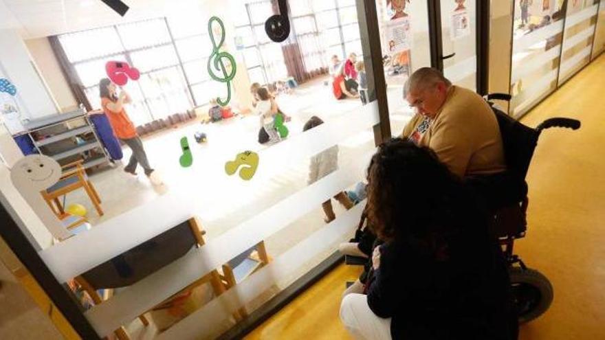 La residente Angelita Álvarez, con una cuidadora, contempla a los niños jugando.