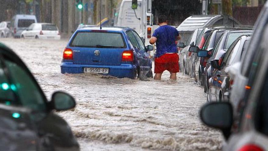 Un conductor trata de acceder a su vehículo en medio de un río de agua en la avenida del Doctor Rico de Alicante, anegada por la riada.