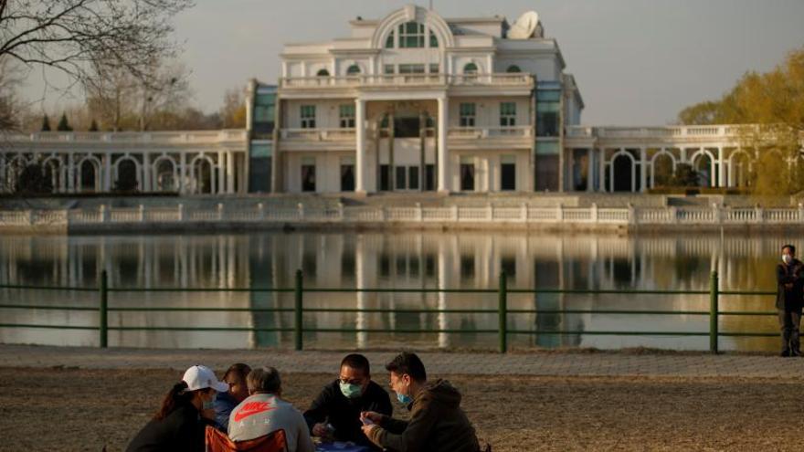 Un grupo de personas juega a las cartas, ayer, en un parque de Pekín.