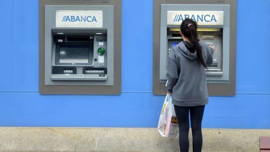 Una cliente de Abanca saca dinero en un cajero. // Gustavo Santos