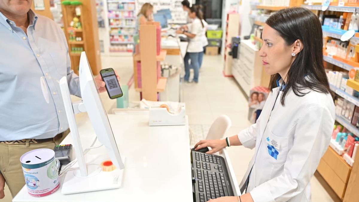 Una farmacéutica atiende a un cliente con el código QR en el móvil.