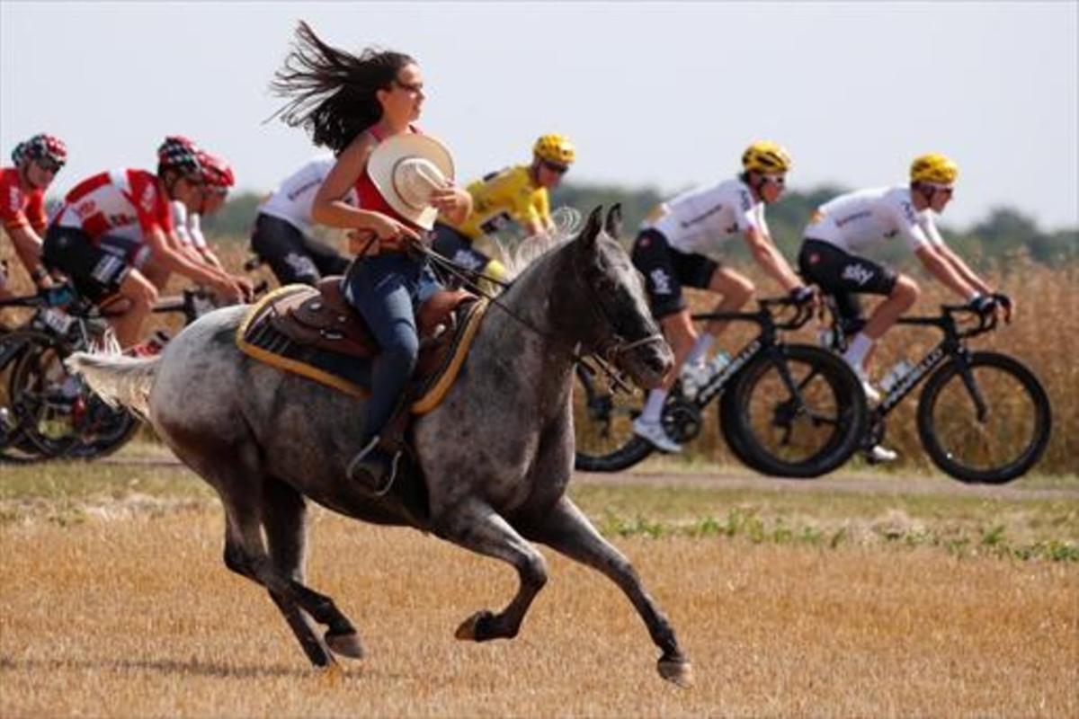 Una amazona trota con su caballo al paso del pelotón del Tour, ayer durante la sexta etapa.