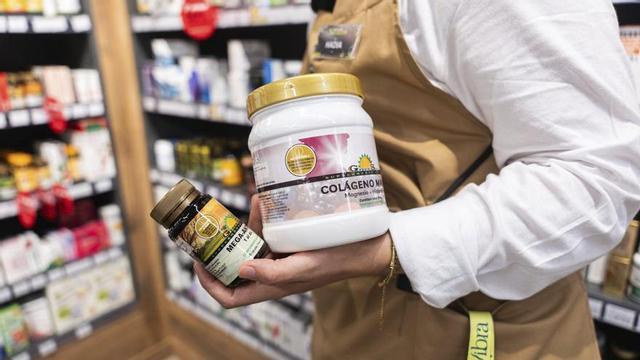 La dependenta d’una herboristeria sosté envasos de complements alimentaris. |