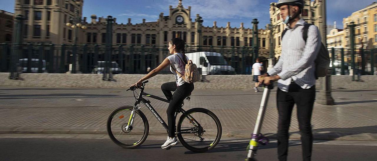 Jóvenes desplazándose en patinete y bicicleta frente a la Estación del Norte de València.  | JM LÓPEZ
