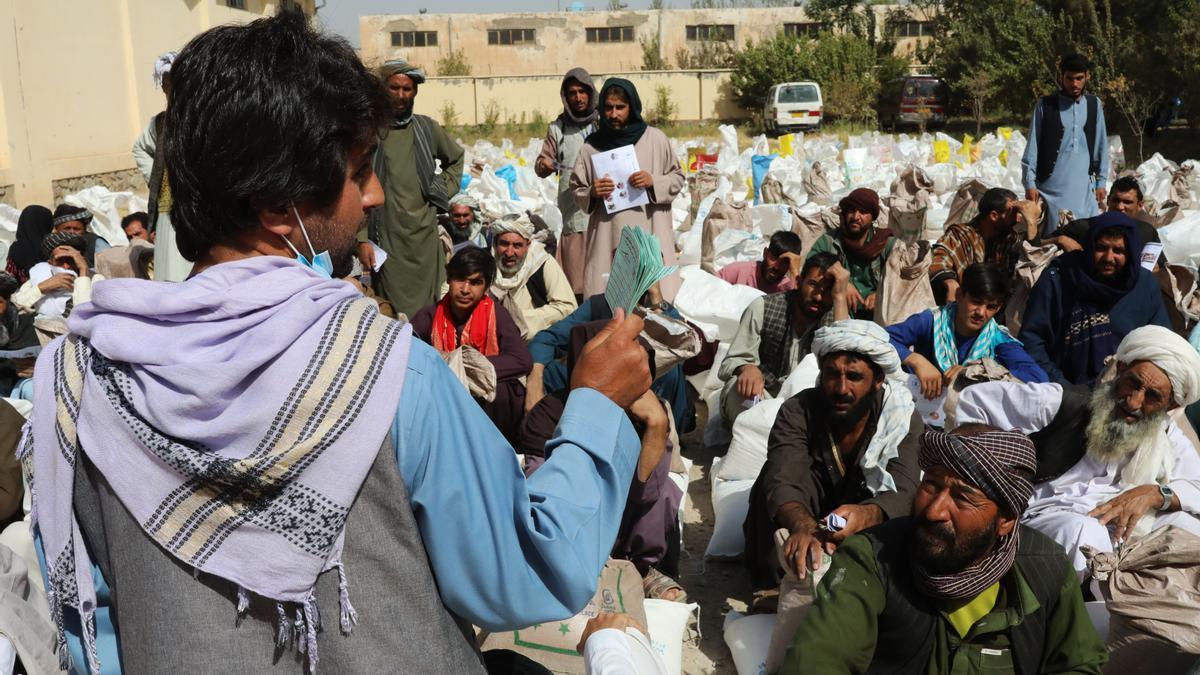 Un voluntario entrega tickets para la entrega de raciones de alimentos en un punto de distribución del Programa Mundial de Alimentos (PMA) en Herat, Afganistán.