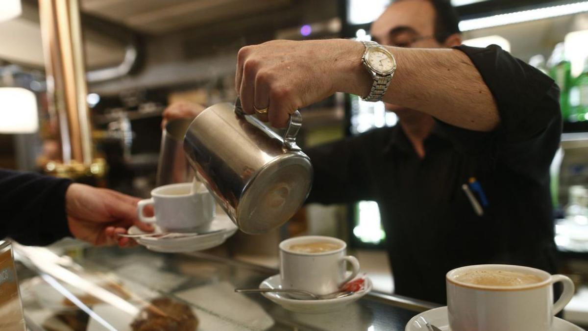 Un camarero echa leche a varios cafés