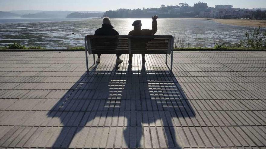 Dos jubilados sentados en un banco en el paseo marítimo de Sada.