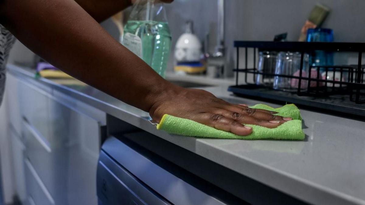 Una empleada de hogar limpia la encimera de la cocina.