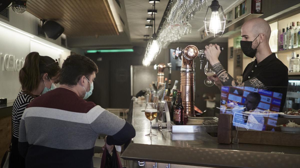 Un camarero sirve una cerveza en la barra de un bar.