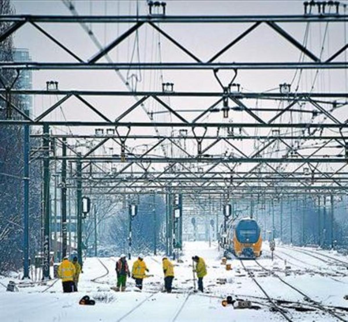 Empleats dels ferrocarrils holandesos netegen les vies a l’Haia. Empleats dels ferrocarrils holandesos netegen les vies a l’Haia.