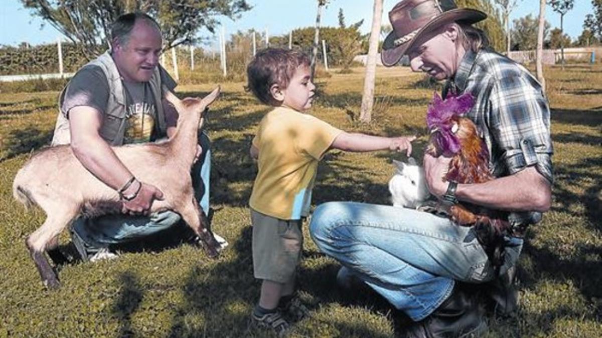 Tocar y jugar 8Ramon Sala, con sombrero, y Cesc Lliberia muestran unos animales al pequeño Hugo en la granja escuela La Perdiu de Cabanes.