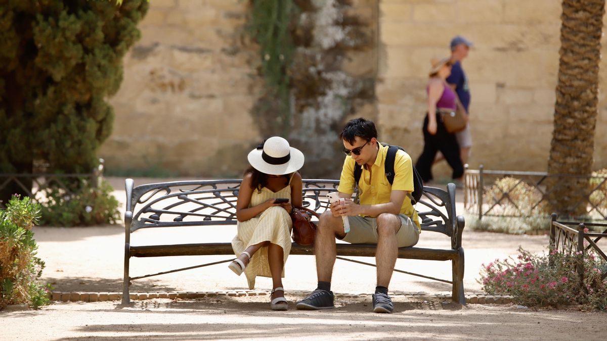 Dos turistas se protegen del sol con gorros y agua en Córdoba.