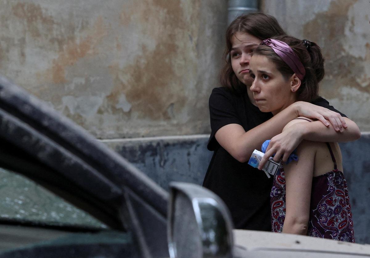 Dos mujeres se abrazan contemplando la destrucción de las bombas sobre un edificio residencial en Leópolis, en Ucrania.