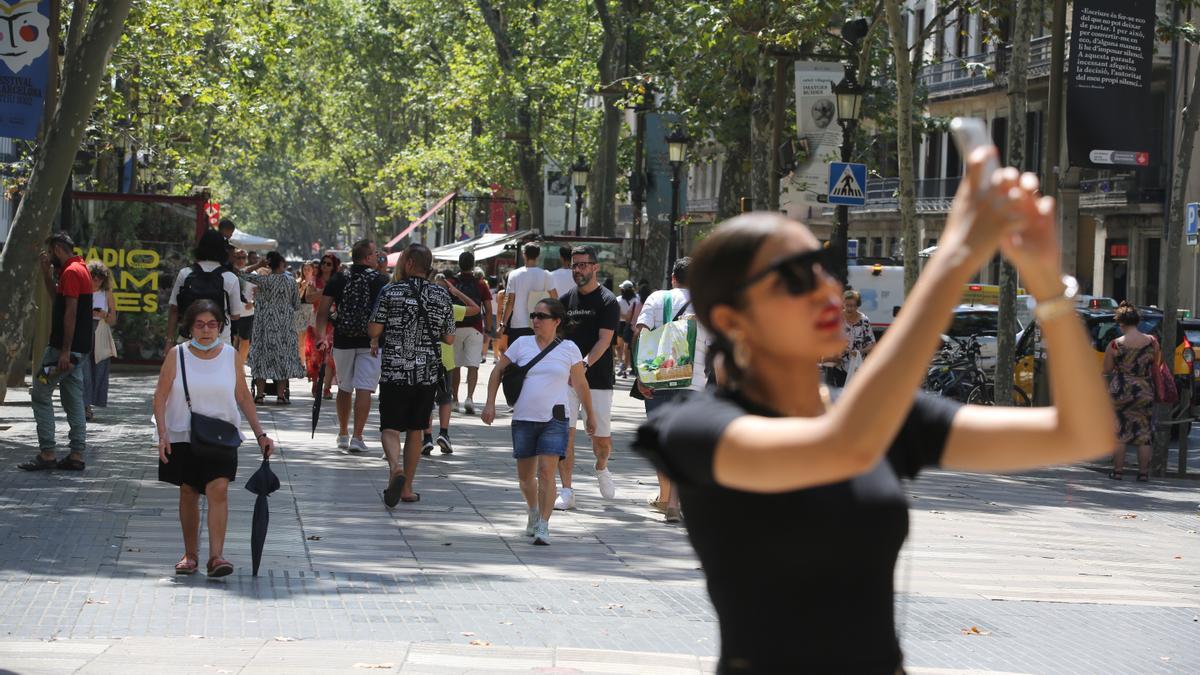 Una turista se hace una foto en la Rambla.