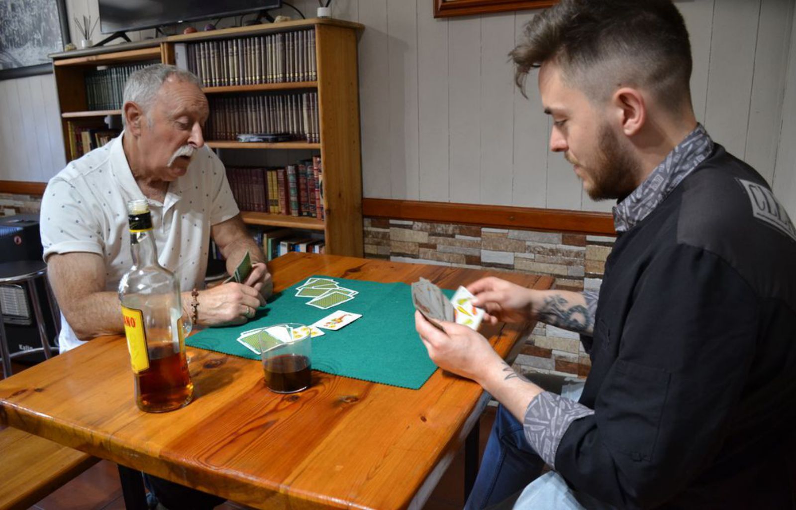 Diego Corteguera y uno de los vecinos de Berbes, Pablo Alonso, simulan una partida de cartas “a la antigua usanza”. 