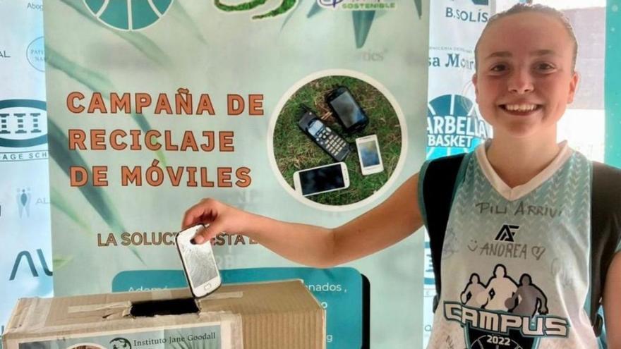 Una jugadora del Avatel Marbella Basket deposita un móvil en la campaña de reciclaje.