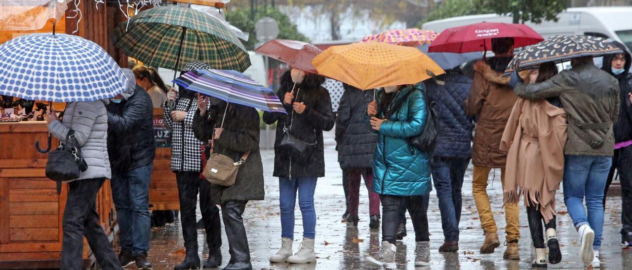 Un grupo de personas se protege de la lluvia con sus paraguas.